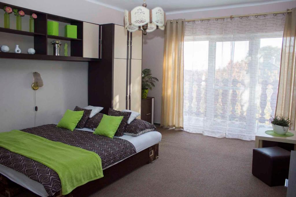 a bedroom with a bed with green pillows and a window at Apartment Gyenesdias 15 in Gyenesdiás