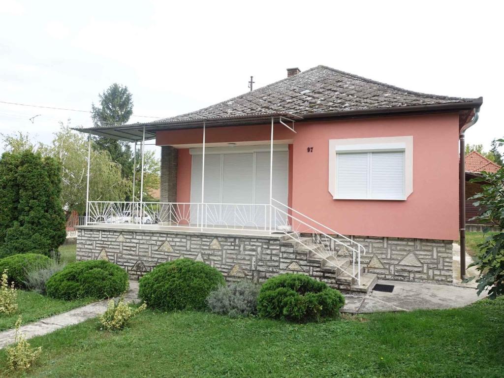 フォニョードにあるHoliday home in Fonyod/Balaton 18592のピンクの家(ポーチ、バルコニー付)