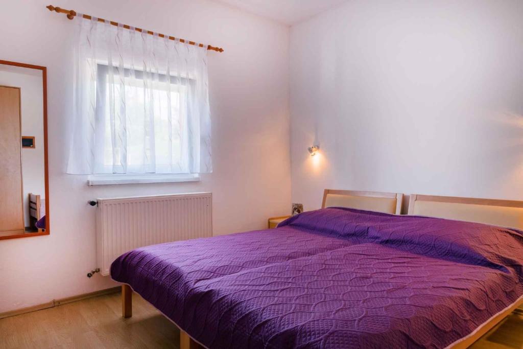 a bedroom with a purple bed and a window at Apartment in Pula/Istrien 11168 in Veli Vrh
