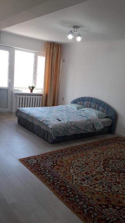 1 dormitorio con cama y alfombra en el suelo en Светлая квартира для гостей, en Kyzylorda