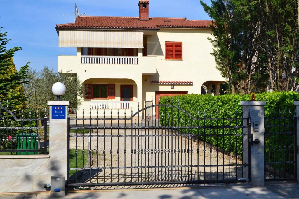 a black gate in front of a white house at Apartment Valbandon 13 in Štinjan