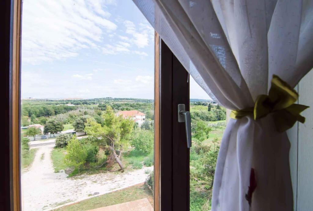 een raam met een gordijn en uitzicht op een veld bij Apartment in Banjole - Istrien 11157 in Banjole