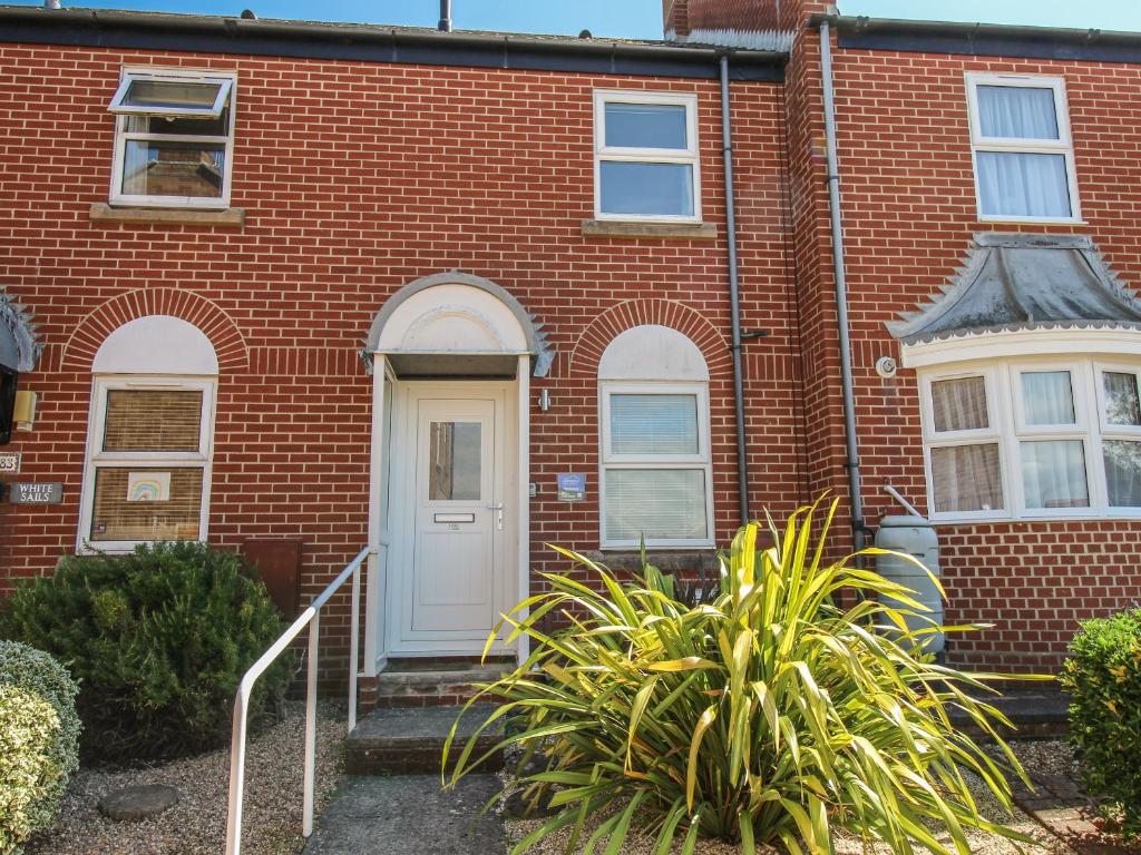 a red brick house with a white door and stairs at Rockpools in Weymouth