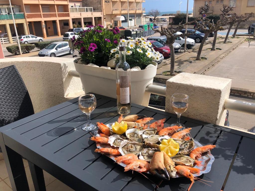 un plato de marisco en una mesa con copas de vino en Villa Magaly T4 à 50 m de la plage de Valras centre, en Valras-Plage