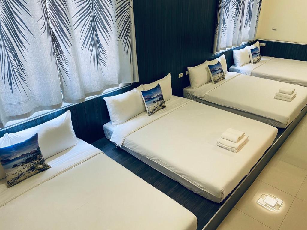 three beds in a room with white sheets and pillows at 舞艾湖民宿 in Hsing-wen