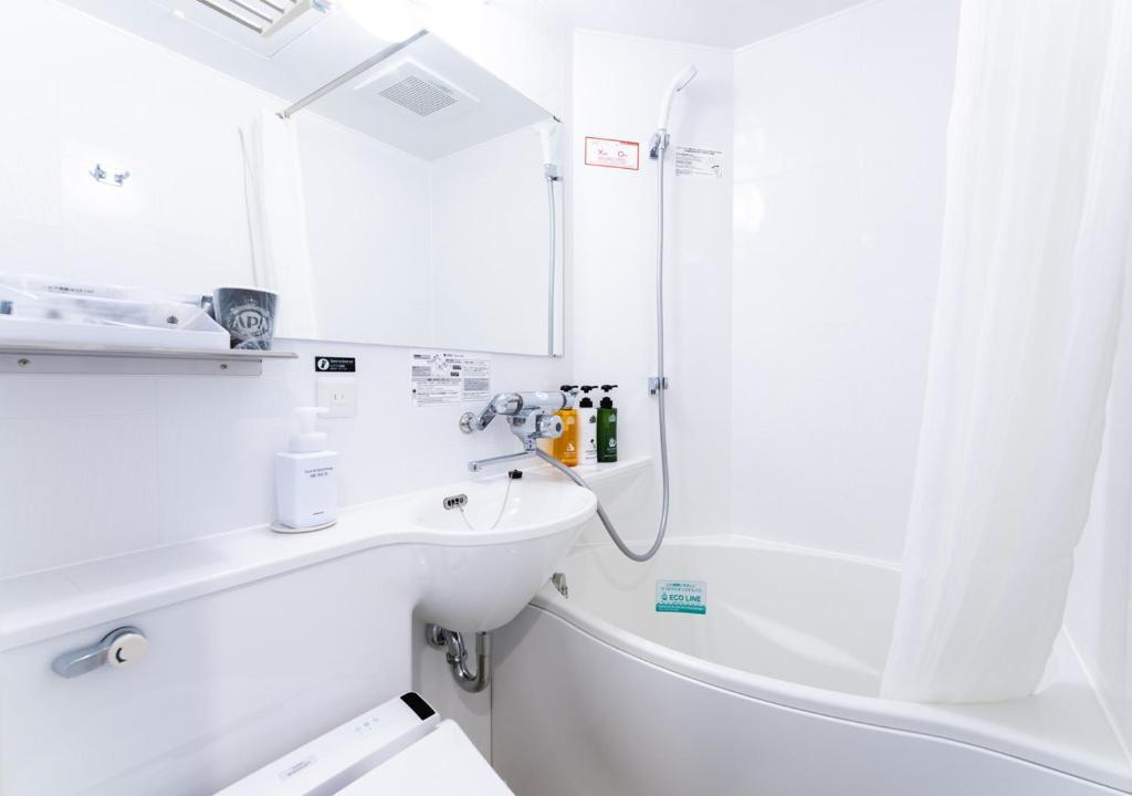 a white bathroom with a sink and a shower at APA Hotel Ningyocho Ekikita in Tokyo