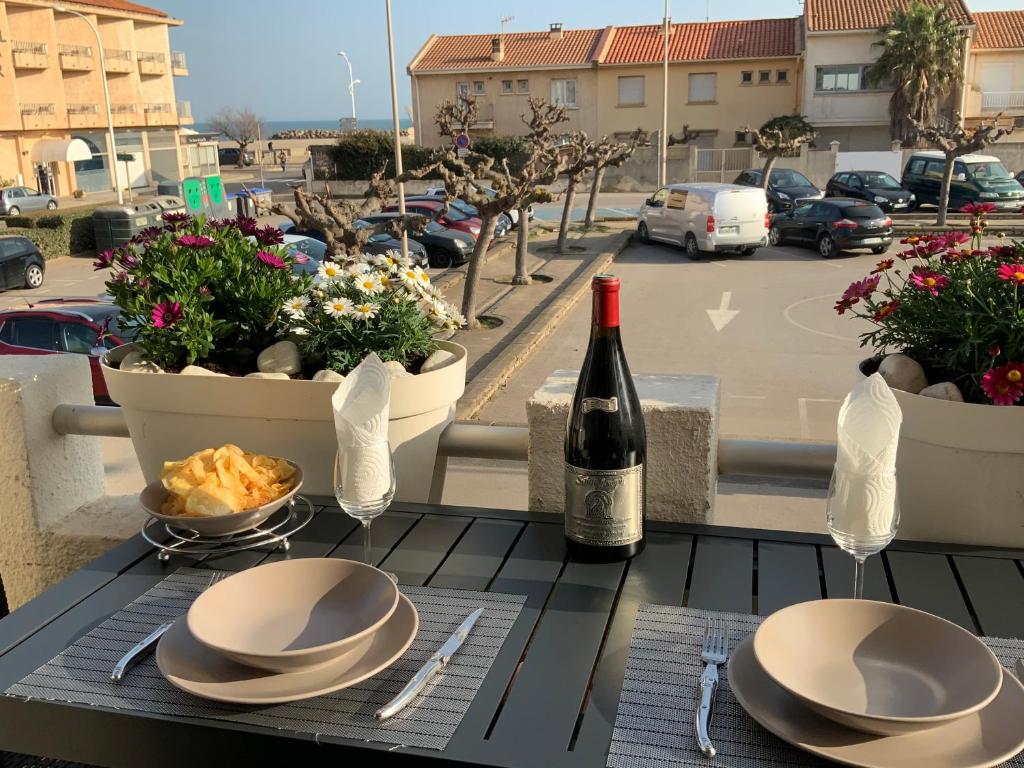 una mesa con una botella de vino y un plato de comida en Villa Magaly T4 à 50 m de la plage de Valras centre, en Valras-Plage