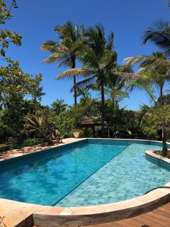 a swimming pool with palm trees in the background at Casa Bromélia Green in Itacaré