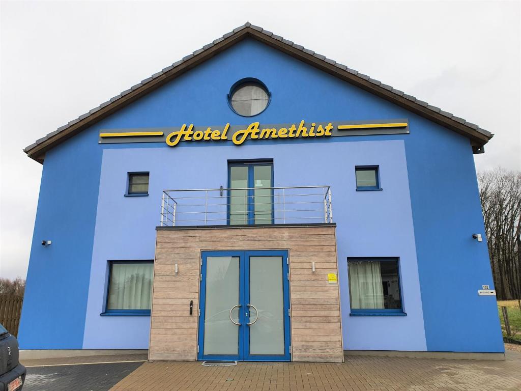 un bâtiment bleu avec un panneau sur lequel figure un panneau dans l'établissement Hotel Amethist, à Ramsel