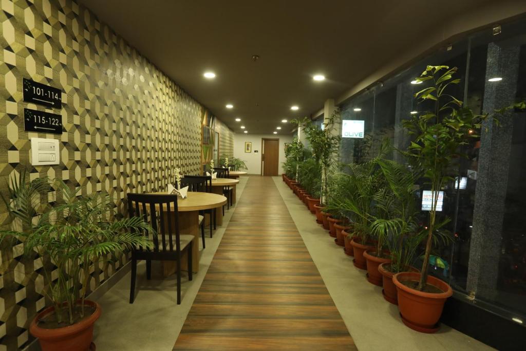 a restaurant with tables and chairs and potted plants at VIPs Hotel Olive in Siliguri