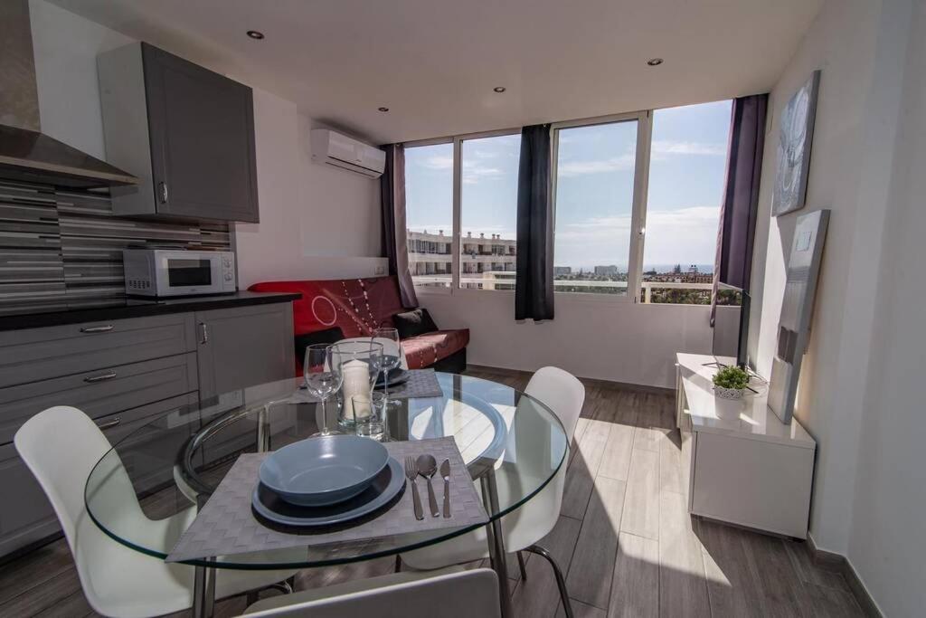 uma cozinha com uma mesa de vidro e cadeiras num quarto em Los Molinos apartment Ocean View em Playa del Inglés