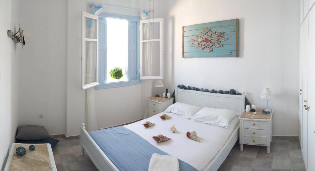 a white bedroom with a bed with shoes on it at Symi . VILLA CALME (Sur la Mer). in Symi