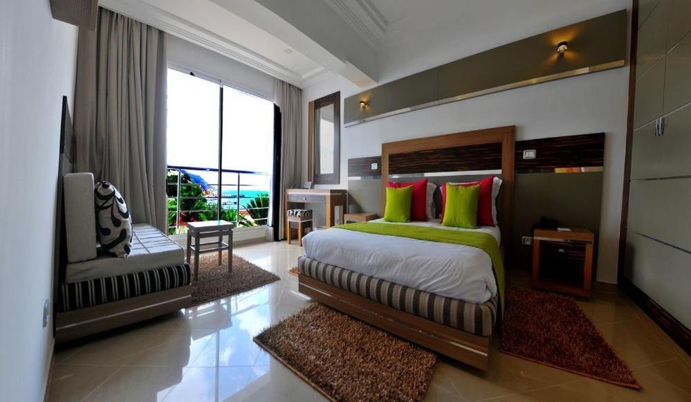 um quarto com uma cama grande com almofadas verdes e vermelhas em Marina Prestige Tabarka em Tabarka