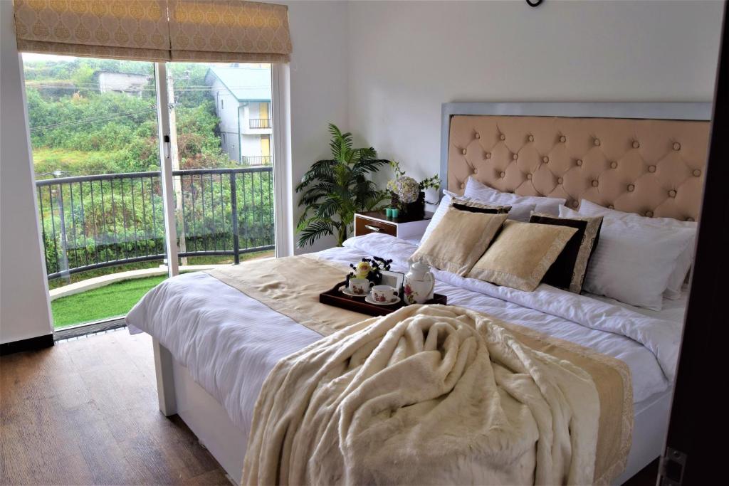 a bedroom with a large bed with a large window at Lake Infinity Luxury Condos in Nuwara Eliya