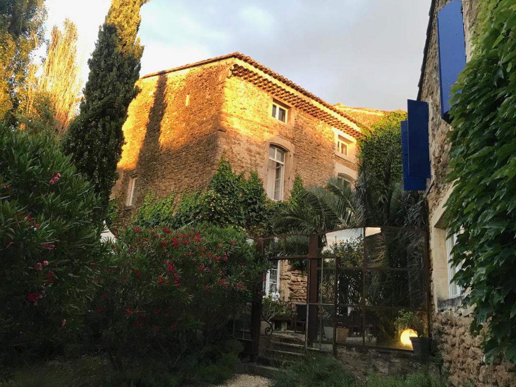 un bâtiment en briques avec des arbres et des fleurs devant lui dans l'établissement Les Aiguières en Provence, à Suze-la-Rousse