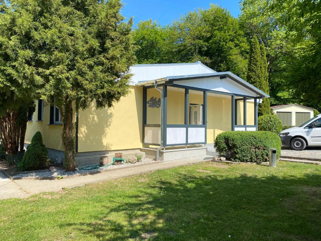 ein kleines gelbes Haus mit einem Baum in der Unterkunft Feriendomizil Achtern Öwer in Lohme