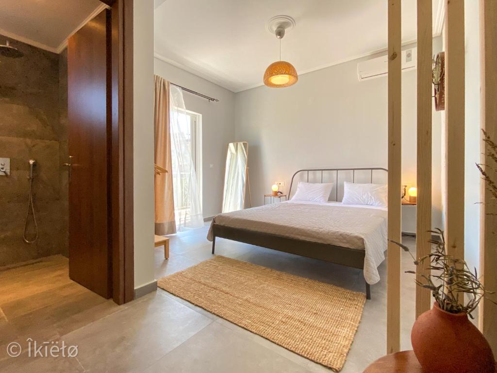um quarto com uma cama e uma cabina de duche ao nível do chão em Theros Lux Apts. em Plános