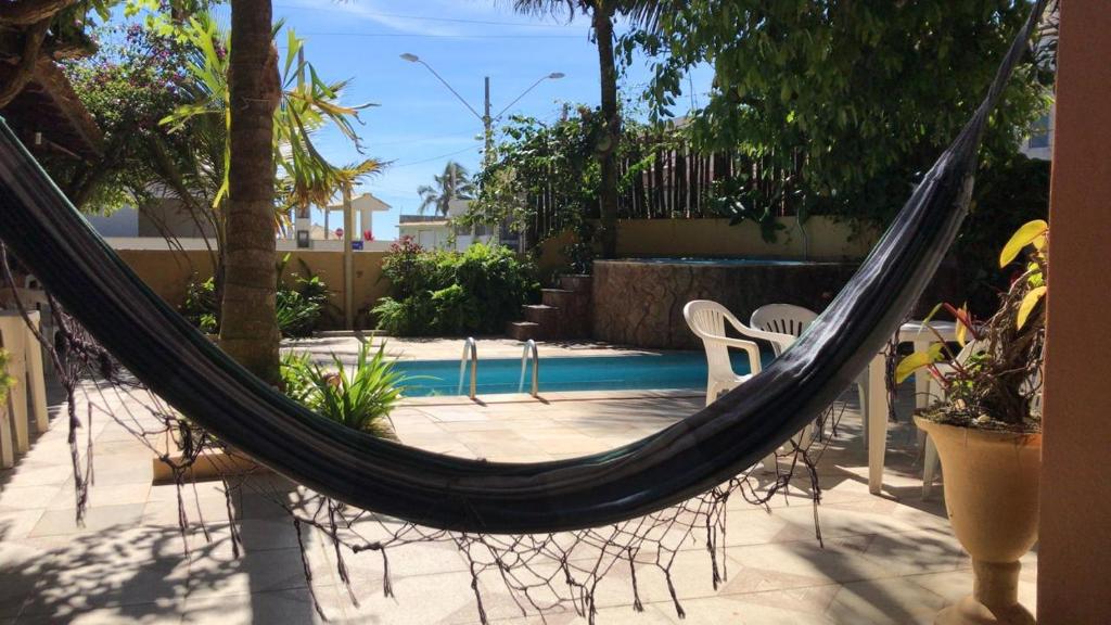 a hammock in a backyard with a pool at Pousada Miramar in Marataizes