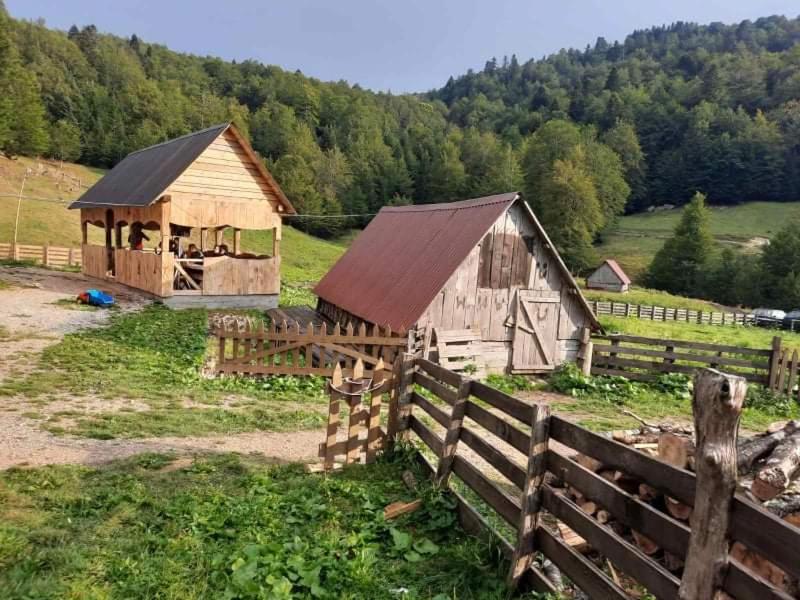 a wooden barn in a field next to a fence at Dulović - KATUN POTOCI in Kolašin