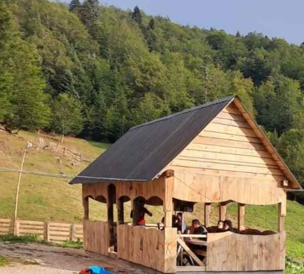 a large wooden barn with people sitting in it at Dulović - KATUN POTOCI in Kolašin