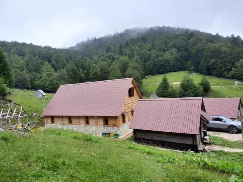 a log cabin with a car parked in a field at Dulović - KATUN POTOCI in Kolašin
