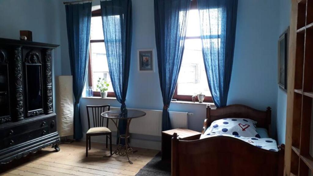 a bedroom with a bed and a table and two windows at Charmante Dorfschule in Hohenhameln