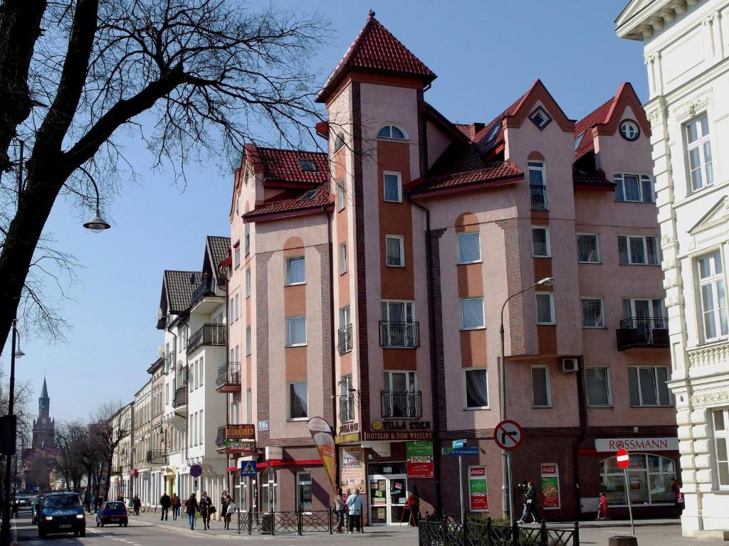 a large building with a tower on a city street at Villa Eden & Restaurant in Ełk