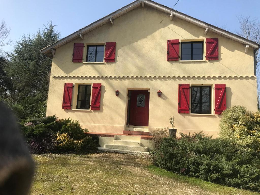 una casa con persianas rojas y una puerta roja en Domaine Pierrot, en Laujuzan