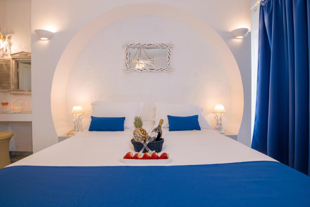 a white bed with blue pillows and fruit on it at Seagull Hotel and Apartments in Agia Marina Nea Kydonias