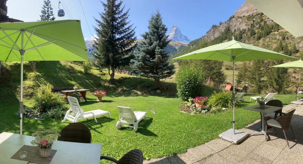 un patio con sillas y sombrillas en el césped en Hotel Plateau Rosa en Zermatt