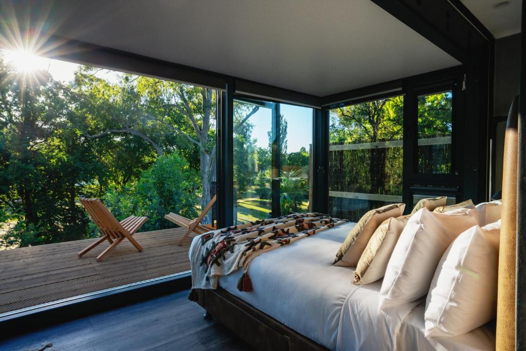 a bedroom with a large bed in front of a large window at Castlemaine Gardens Luxury Glamtainer in Castlemaine
