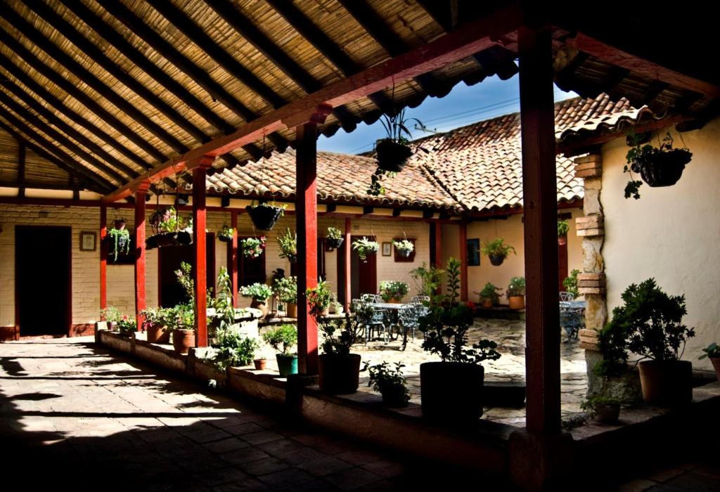 an outdoor patio with potted plants and a pergola at Hotel Cacique Real in Zipaquirá