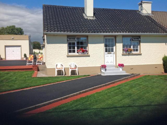 une maison blanche avec deux chaises devant elle dans l'établissement Village Cottage, à Dunkineely