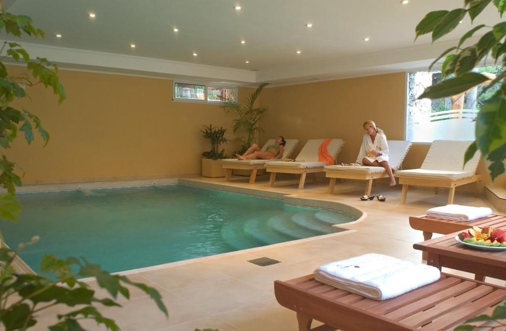una piscina en una sala de estar con 2 personas sentadas en sillas en Pillmayken Apart&Spa Mar de las Pampas en Mar de las Pampas
