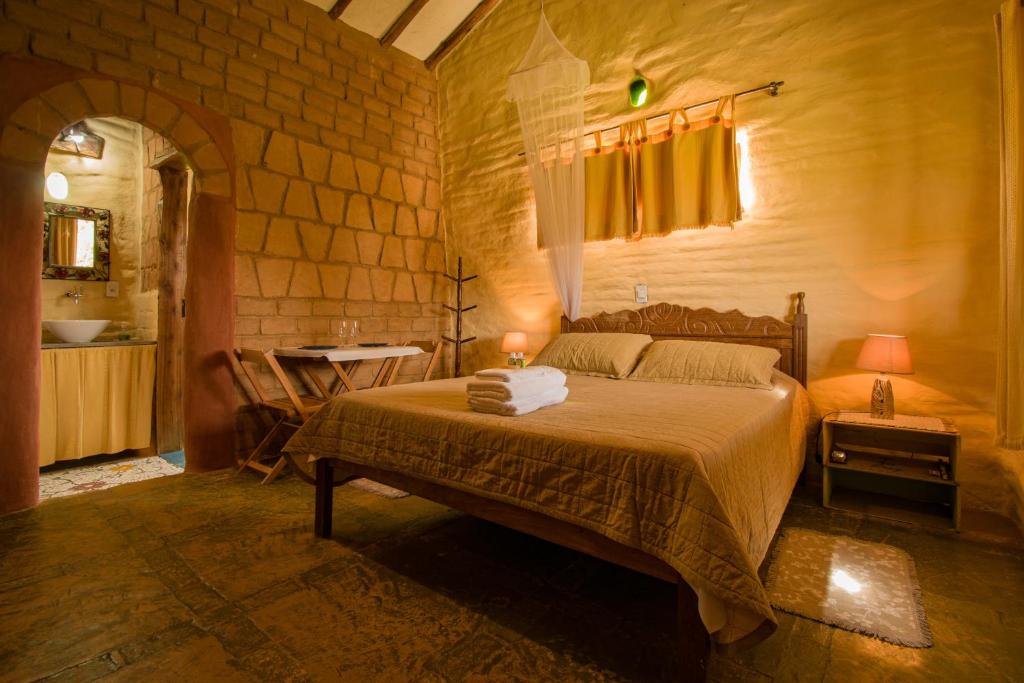 een slaapkamer met een bed in een stenen muur bij Pousada Ceu e Serra in Carrancas
