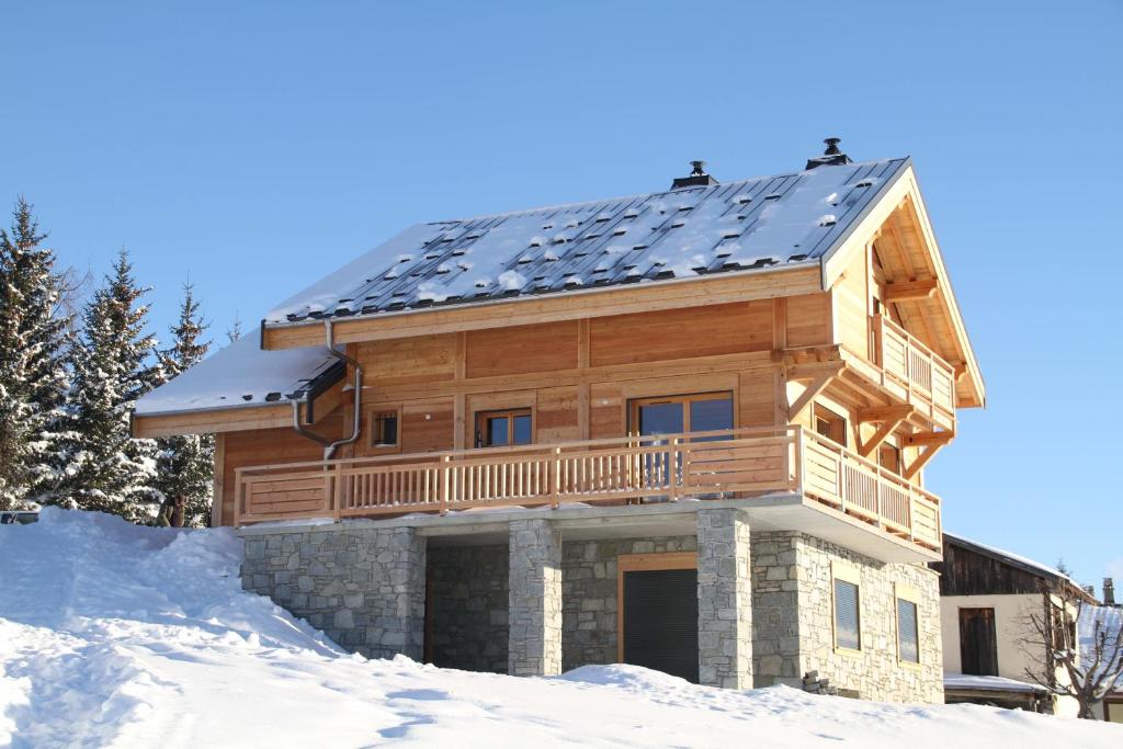 a log home with a solar roof in the snow at Chalet Les Hellebores in La Toussuire