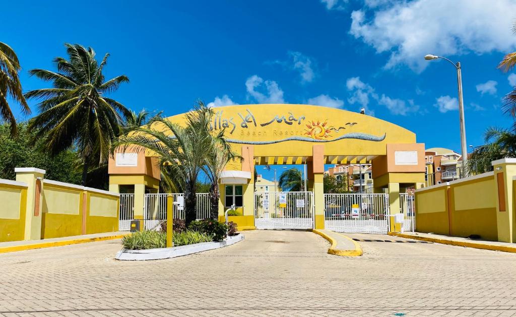 un bâtiment jaune avec un portail et des palmiers dans l'établissement Villas Del Mar Beach Resort, à Loiza
