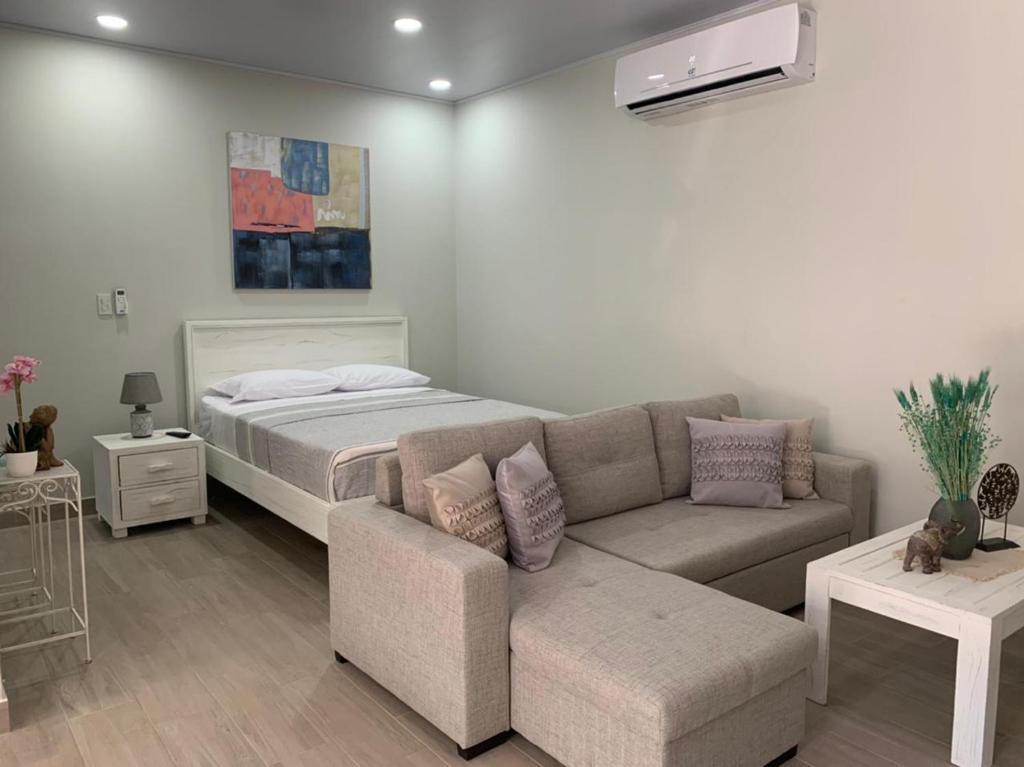 ein Wohnzimmer mit einem Sofa und einem Bett in der Unterkunft Apartamentos Ganesha Jacó in Jacó