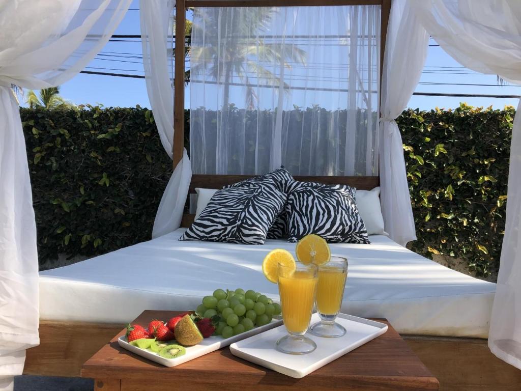 a bed with a tray of fruit and two glasses of juice at Pousada Tortugas in Guarujá