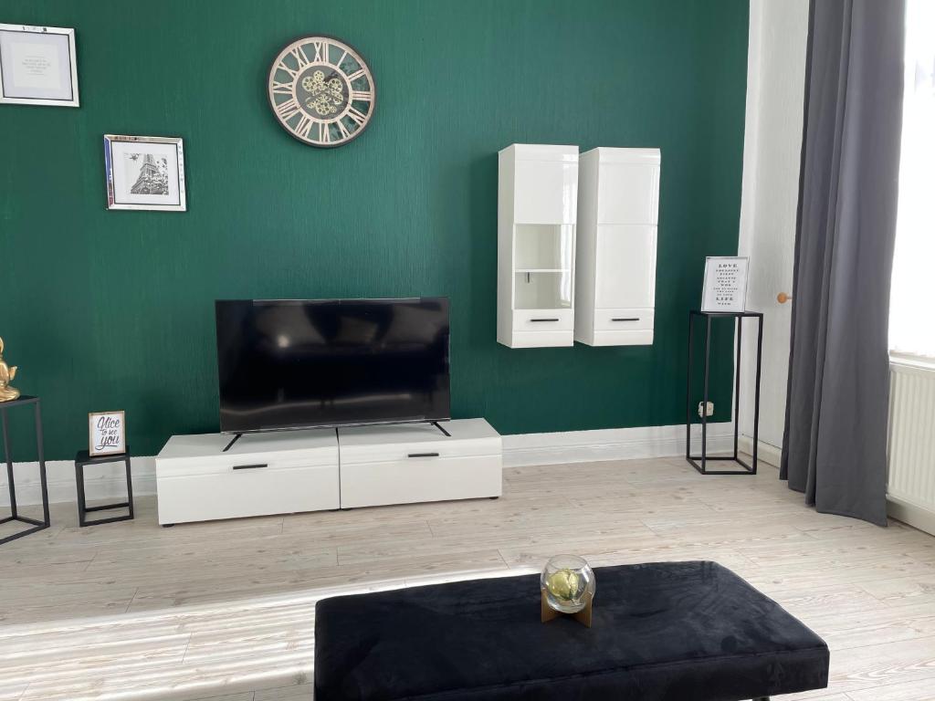 uma sala de estar com televisão e uma parede verde em Sky Night Suite em Düren - Eifel
