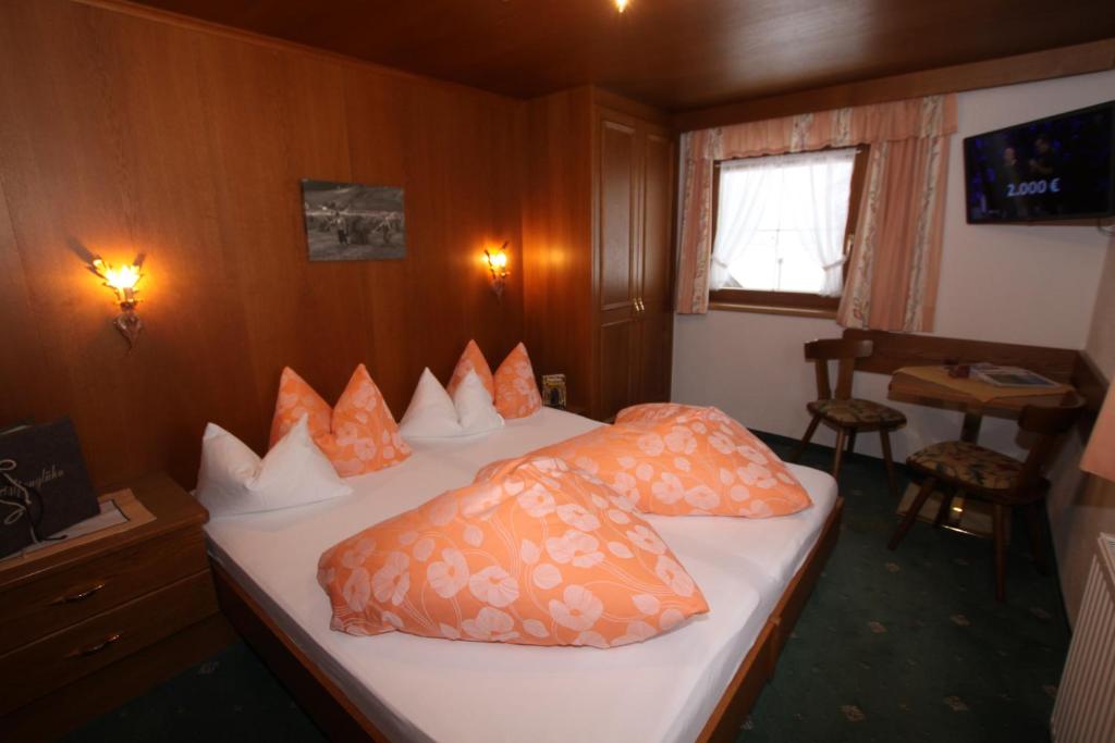 1 dormitorio con 1 cama con almohadas de color naranja en Haus Alpenglühn, en Längenfeld