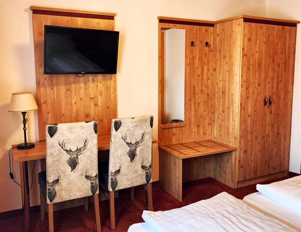 a bedroom with a desk and a tv and two chairs at Hotel Paintner in Germering