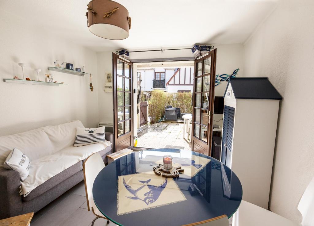 un soggiorno con tavolo in vetro e divano di La Kaz a Courseulles-sur-Mer