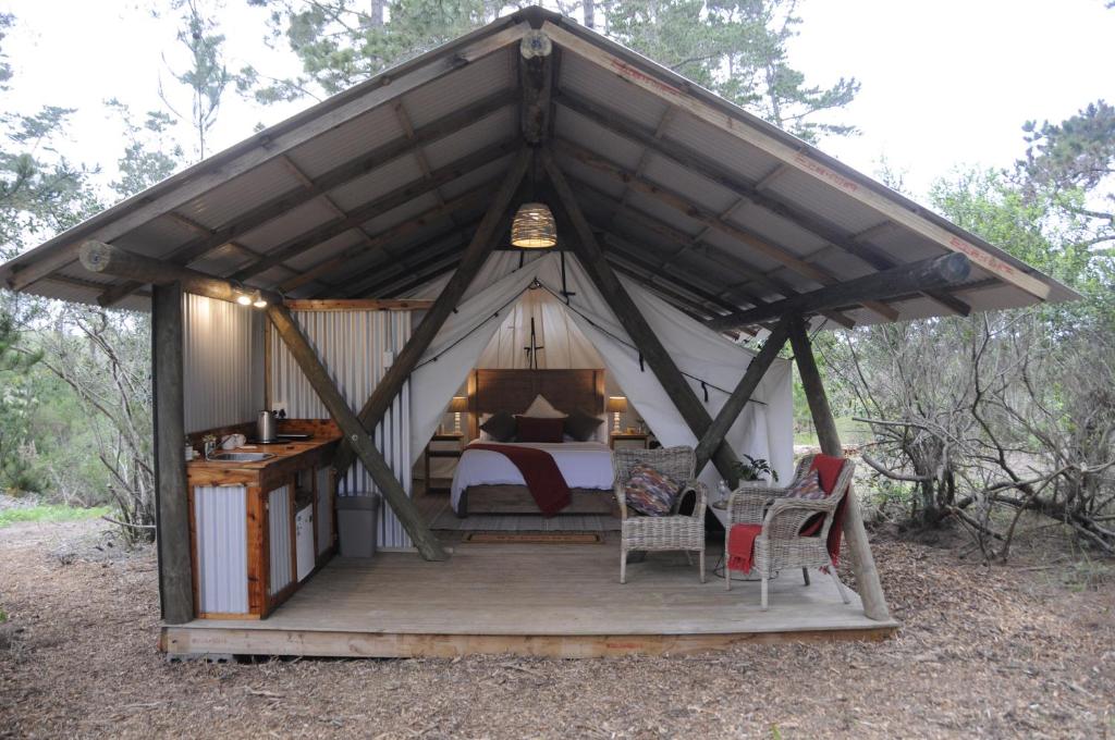 a bedroom in a tent with a bed and chairs at Heritage Glamping, Woodlands tent in Wilderness