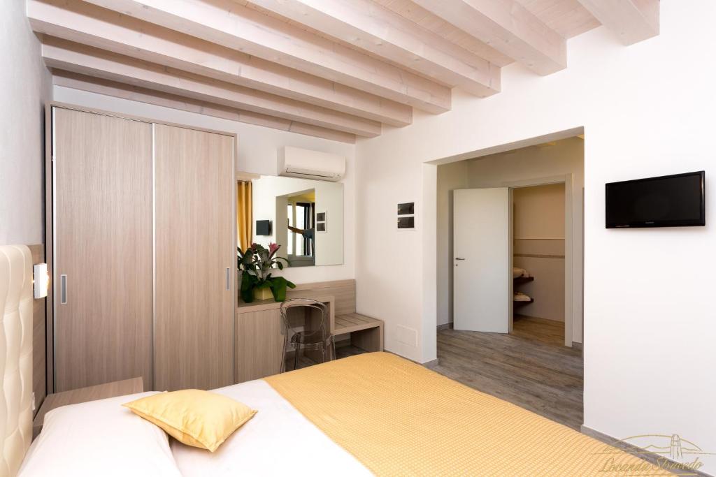 a bedroom with a bed and a desk and a television at Locanda Stravedo in Pellestrina