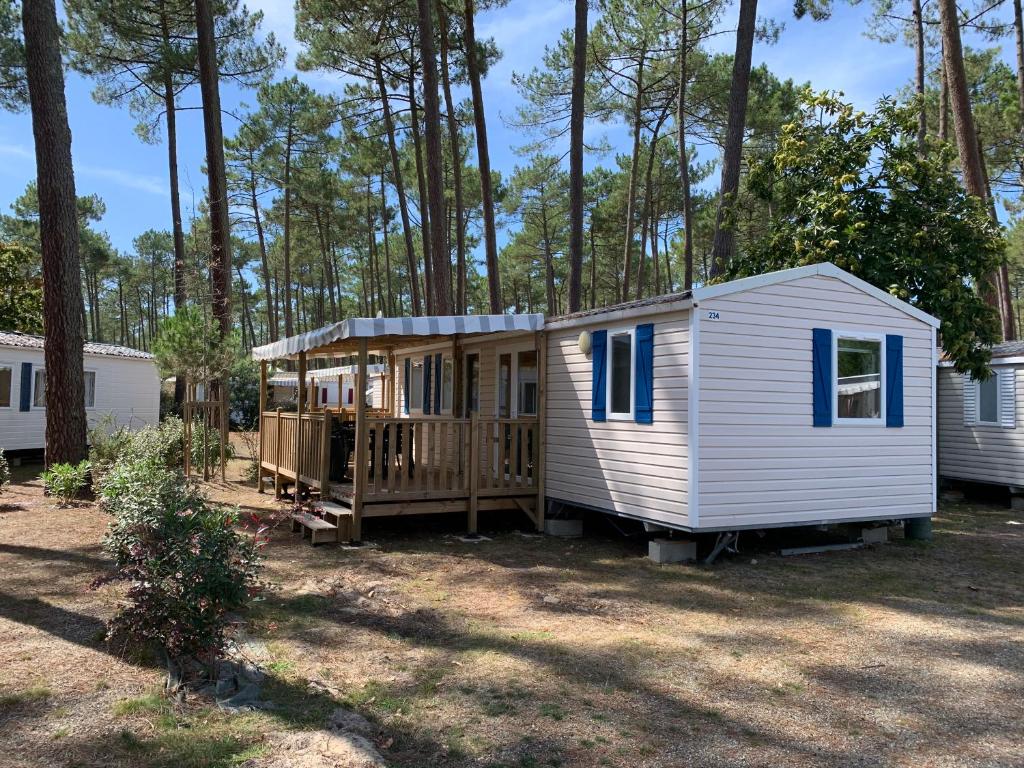 a white tiny house sitting in the woods at Mobil home 6/8 pers Les Dunes de Contis in Saint-Julien-en-Born