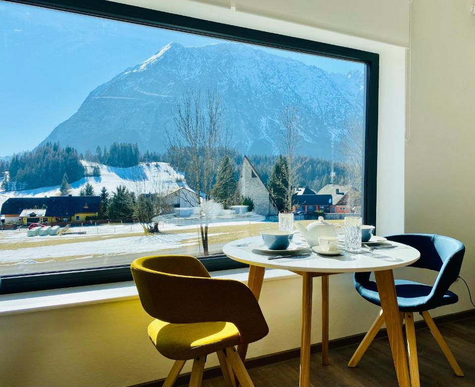 a table and chairs in front of a window with a mountain at Haus Stadler - Self Check-in in Tauplitz