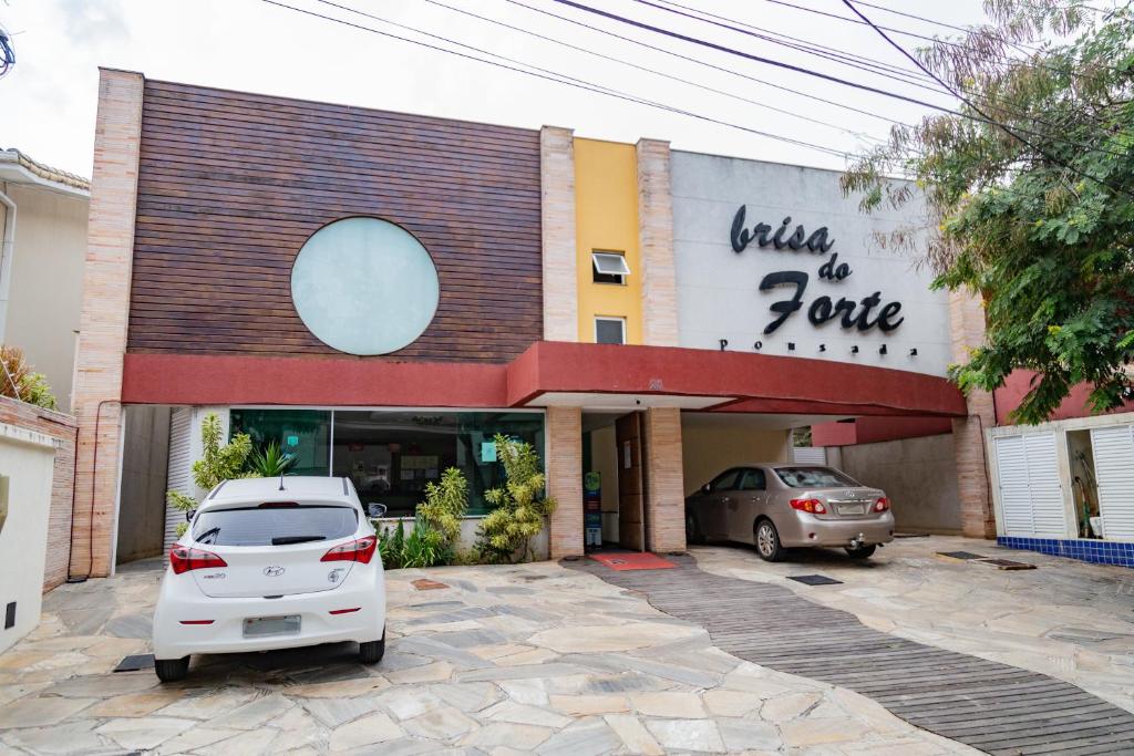 un coche blanco estacionado en un estacionamiento frente a una tienda en Pousada Brisa do Forte, en Cabo Frío