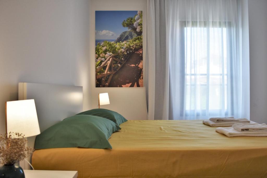 um quarto com uma cama com um quadro na parede em Sky Blue Apartment em Ponta Delgada