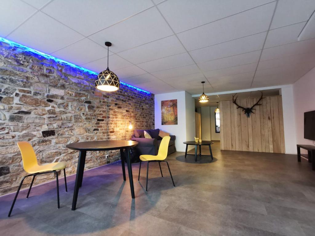 a room with a stone wall and a table and chairs at La Librairie in Francorchamps